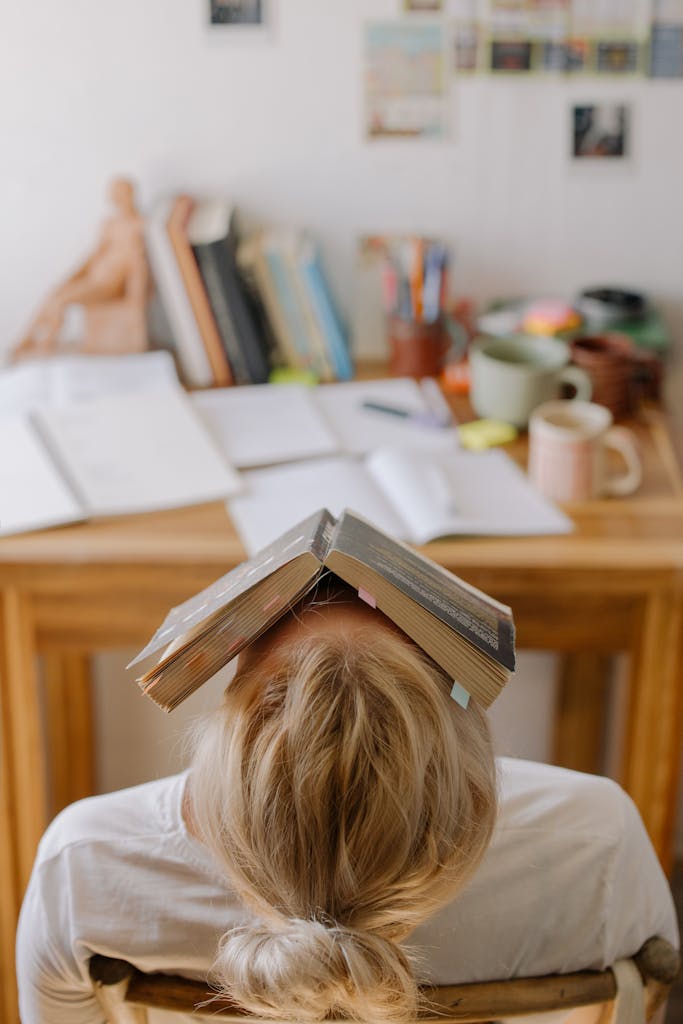 journaling for overwhelm: burnt out woman tilting backward in chair with a book laying on her face